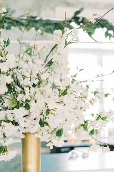 a gold vase filled with white flowers on top of a table