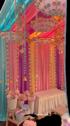 a canopy bed decorated with pink, blue and yellow draping for a baby shower