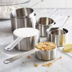 several measuring cups and spoons on a counter with ingredients for making cake in them