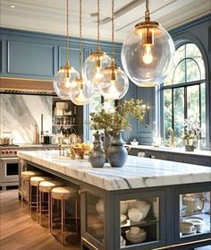 a kitchen with marble counter tops and pendant lights hanging from the ceiling over the island