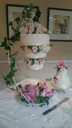 a wedding cake with flowers on it is sitting on a table next to other cakes