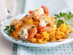 a white plate topped with shrimp and couscous next to a glass of water