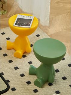 two small stools sitting on top of a rug in front of a table with a magazine