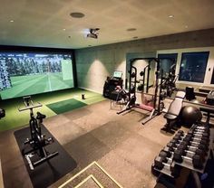 an indoor gym with treadmills, exercise machines and golf simulator on the wall