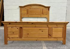 a wooden bed sitting on top of a parking lot next to a white brick wall