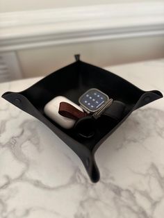 an apple watch sits in a black case on a marble counter