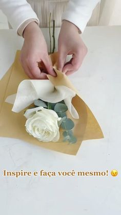 a woman is making a flower arrangement with paper and scissors on the table in front of her