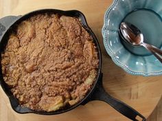 a close up of a pie in a pan on a table with a bowl and spoon