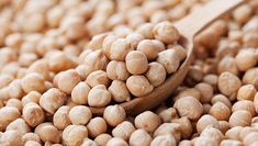 a wooden spoon filled with chickpeas on top of a table