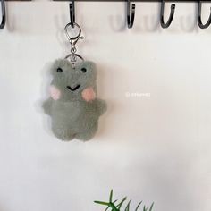 a stuffed animal keychain hanging on a wall next to a potted plant