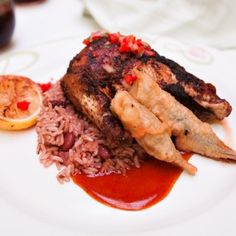 a white plate topped with meat and rice next to an orange slice on a table