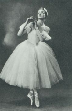 a black and white photo of a woman in a tutu skirt with her hands behind her head