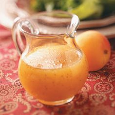 two oranges sitting on a table next to a glass pitcher