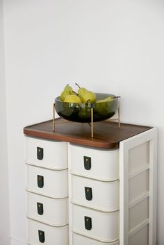 a bowl of fruit sitting on top of a white dresser next to a wooden tray