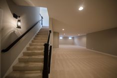 an empty room with carpeted stairs leading to the second floor and light fixture on the wall