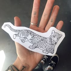 a person holding up a sticker with a drawing of a leopard on it's back