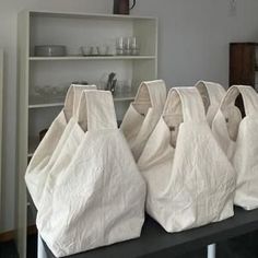 several white bags sitting on top of a table in front of a book shelf filled with books