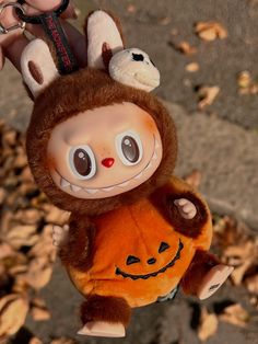 a person holding a stuffed animal in the shape of a monkey with a jack - o'- lantern on its back