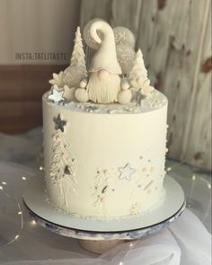 a white frosted cake decorated with snowflakes and santa clause on top is sitting on a table