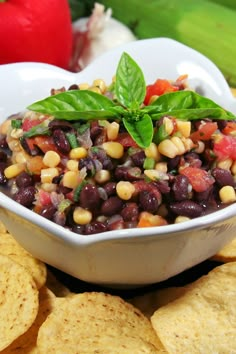 a white bowl filled with black beans and veggies next to tortilla chips