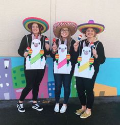 three women in sombreros are holding up signs with the same image on them