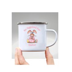 a person holding a white coffee mug with an image of a bunny on the side