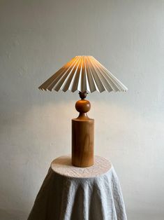 a table lamp sitting on top of a white cloth covered round table next to a wall