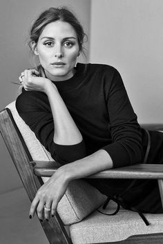 a black and white photo of a woman sitting in a chair with her hand on her chin