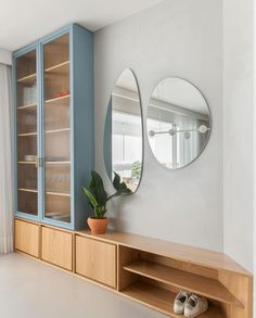 a living room with a large mirror on the wall next to a wooden shelf and shoe rack