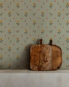 a piece of wood sitting on top of a white shelf next to a wallpaper