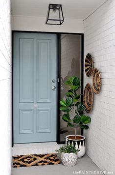 a blue front door with two planters on the side and a black and white checkered rug