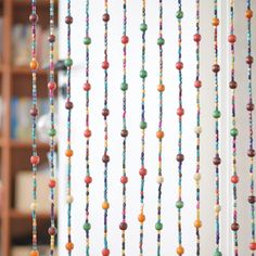 multicolored beads hanging from the ceiling in front of a book shelf and bookshelf