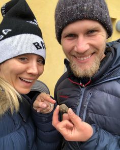 a man and woman standing next to each other holding something in their hands while smiling at the camera