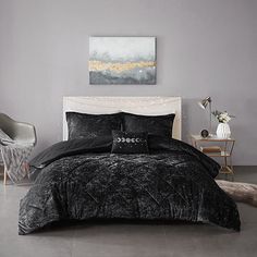 a bedroom with grey walls and black bedding in the corner, along with a painting on the wall