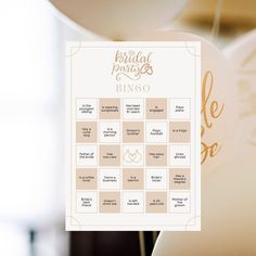 a bridal party game is hanging from the ceiling with gold foil lettering on it