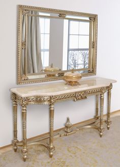 a large mirror sitting on top of a wooden table next to a white and gold wall