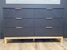 a blue dresser sitting on top of a hard wood floor next to a wall with pictures above it