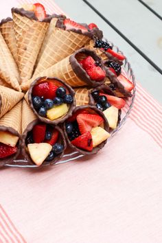 an ice cream sundae with fruit and chocolate toppings on a pink tablecloth