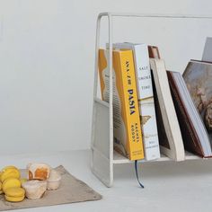 some books are sitting on a shelf next to muffins and other food items