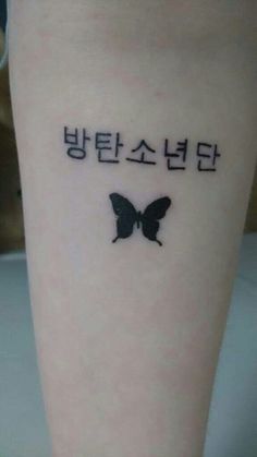 a small black butterfly tattoo on the right leg with words written in korean and english