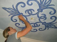 a woman painting a ceiling with blue paint