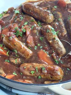 some sausages and carrots in a stew with gravy on the side