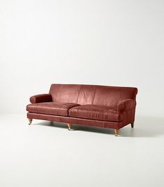 a red leather couch sitting on top of a white floor next to a wooden frame