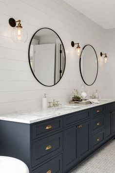 a bathroom with two sinks and three mirrors on the wall next to eachother