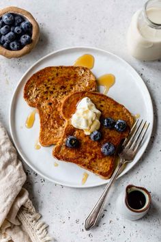 two pieces of french toast on a plate with butter and blueberries next to it