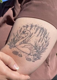 a woman's arm with a swan tattoo on the left side of her body