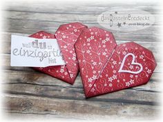 two red heart shaped boxes sitting on top of a wooden table