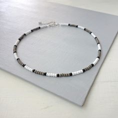 Mens beaded necklace white gray black seed beads. Minimalist unisex choker necklace where a pattern is made with three color seed beads. In this beaded necklace five white glass beads are separated from the five gray glass beads with a single black glass bead between them. The same pattern goes all along the necklace. All beads are glass beads.  Unisex style choker necklace for men or for women. The glass seed beads are about 4 mm.    The necklace closes with a lobster clasp in a chain.   Length Seed Bead Necklace For Men, Beaded Necklace White, Mens Beaded Necklaces, Black Seed, Necklace White, Grey Glass, Necklace For Men, Seed Bead Necklace, Unisex Style