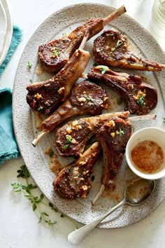 a white plate topped with lamb chops and dipping sauce