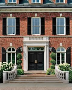 a large brick house with black shutters and white trim on the front door is shown